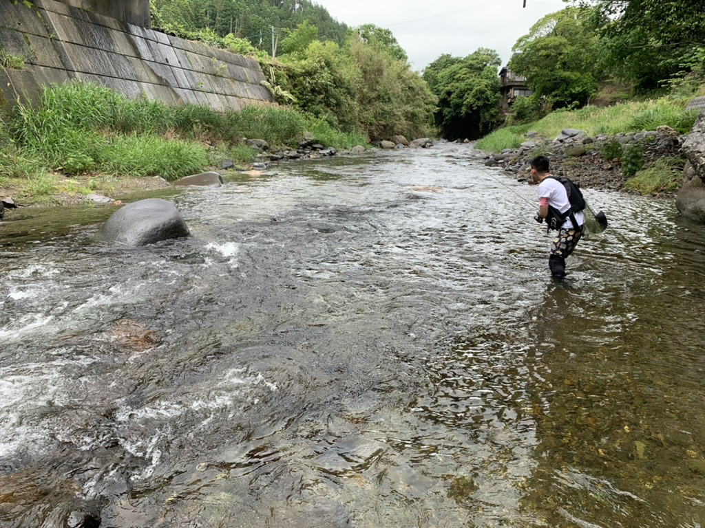 大自然に囲まれた渓流で釣りをする男性